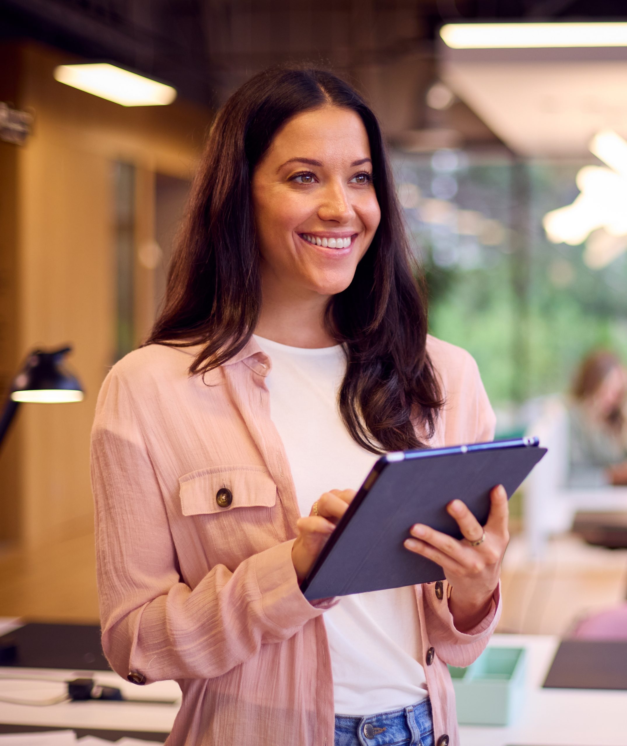 A women smiling and holding a tablet